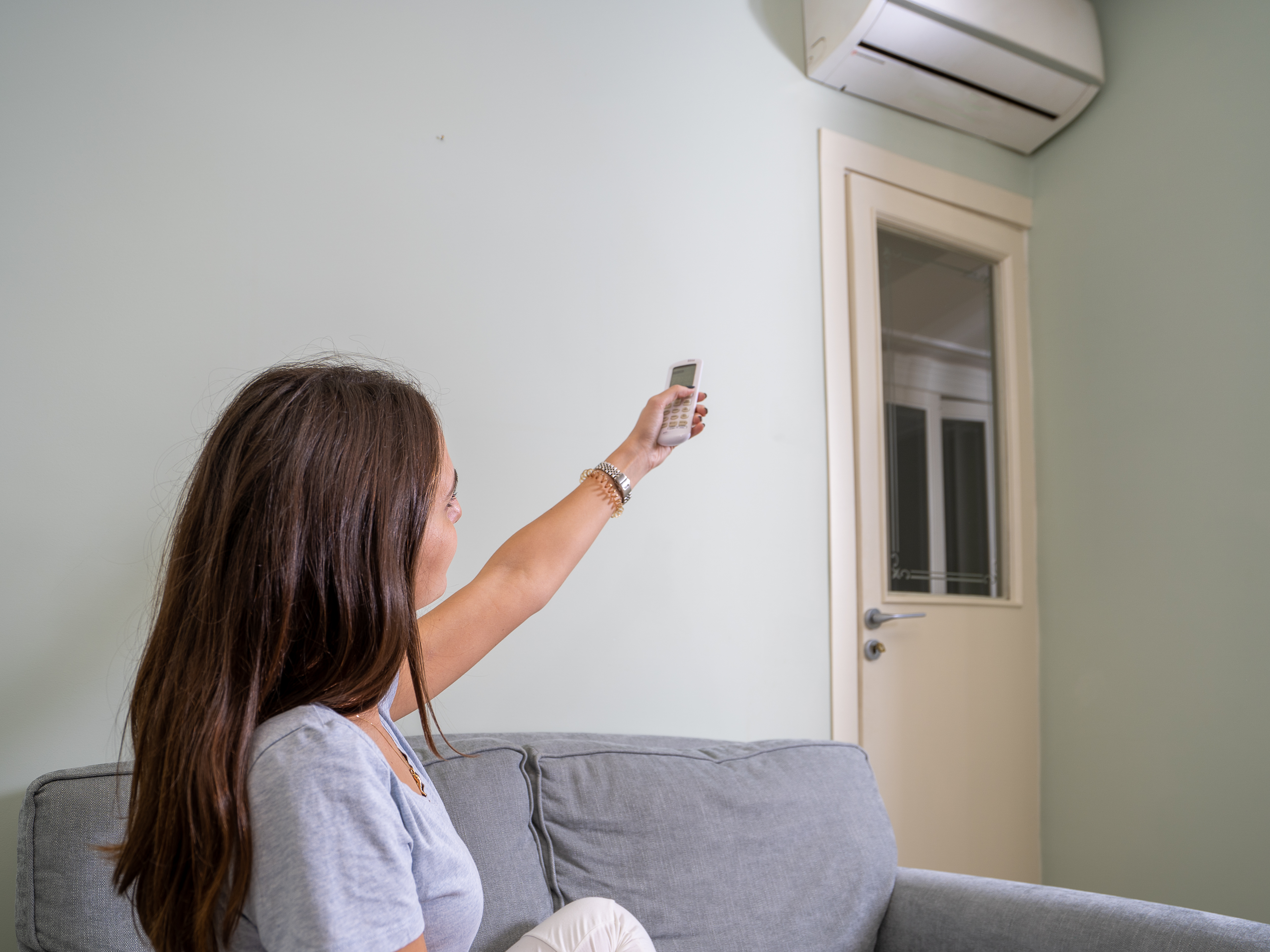/media/nevpq42c/woman-adjusting-air-conditioner-at-home-with-remot-2026-03-23-23-25-43-utc.jpg